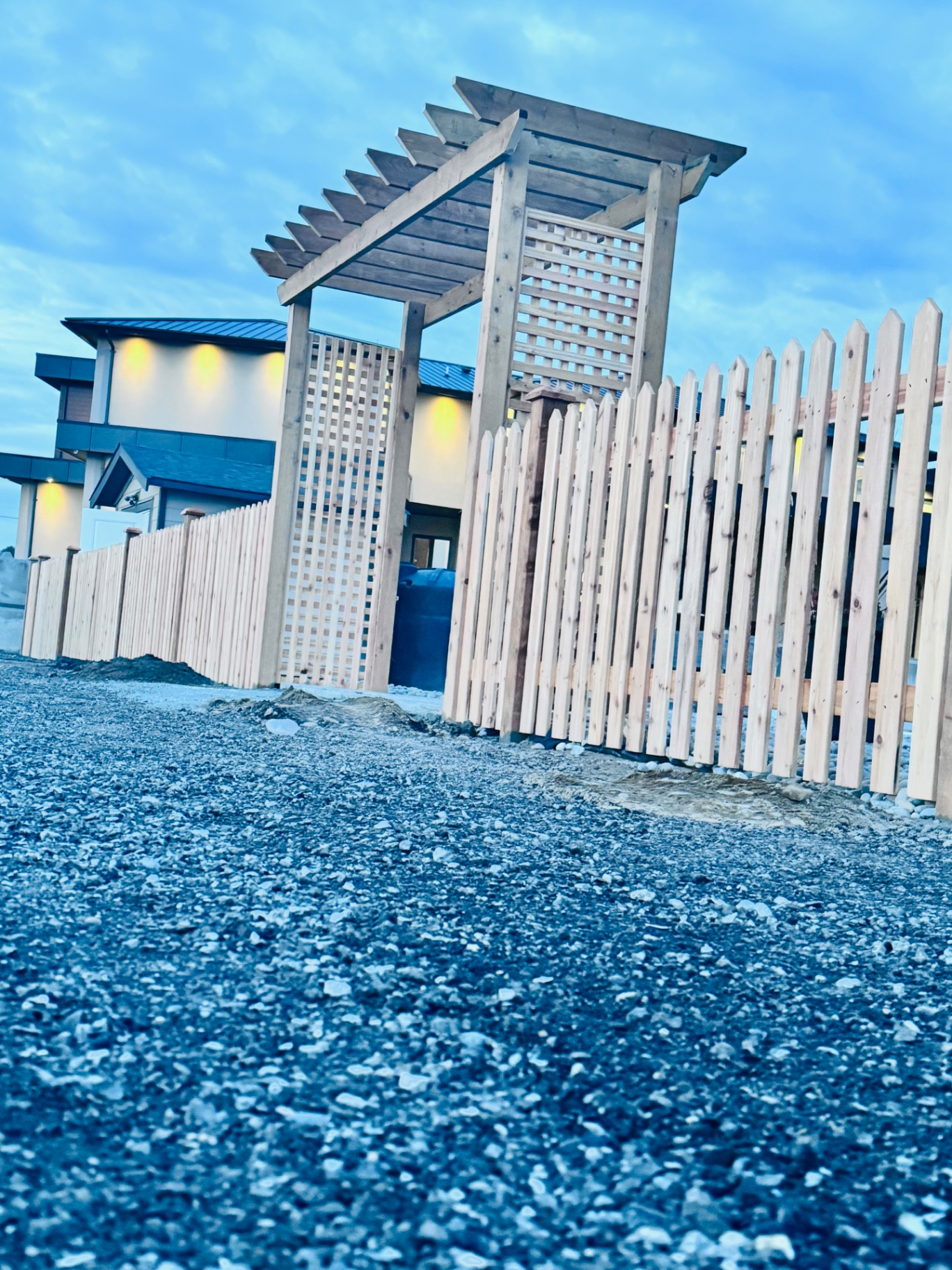 Cedar pergola with lattice privacy screens beside a cedar picket fence at dusk