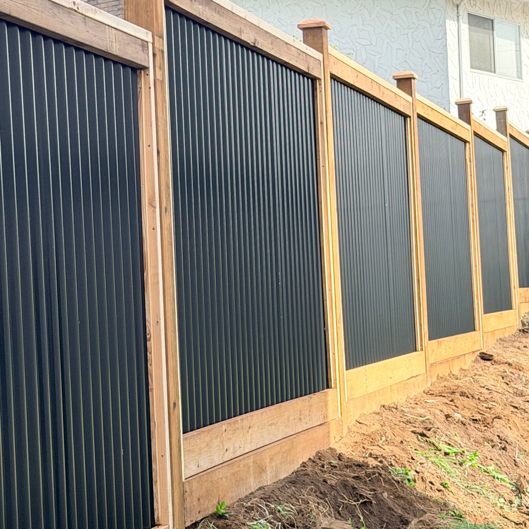 Black corrugated metal privacy fence panels framed in western red cedar