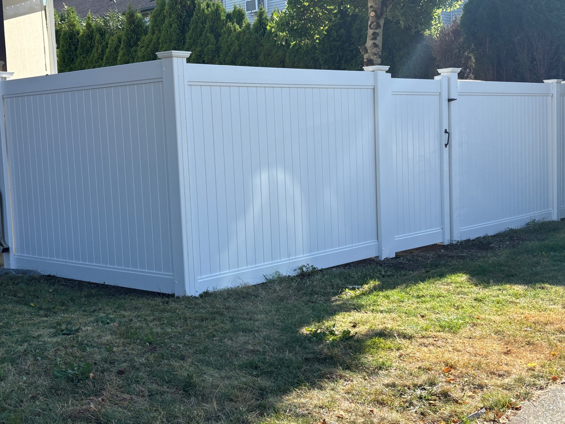 White vinyl privacy fence with a matching gate around a backyard